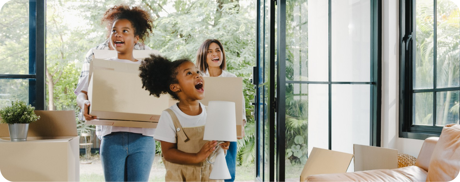 Happy family carrying moving boxes in their new home